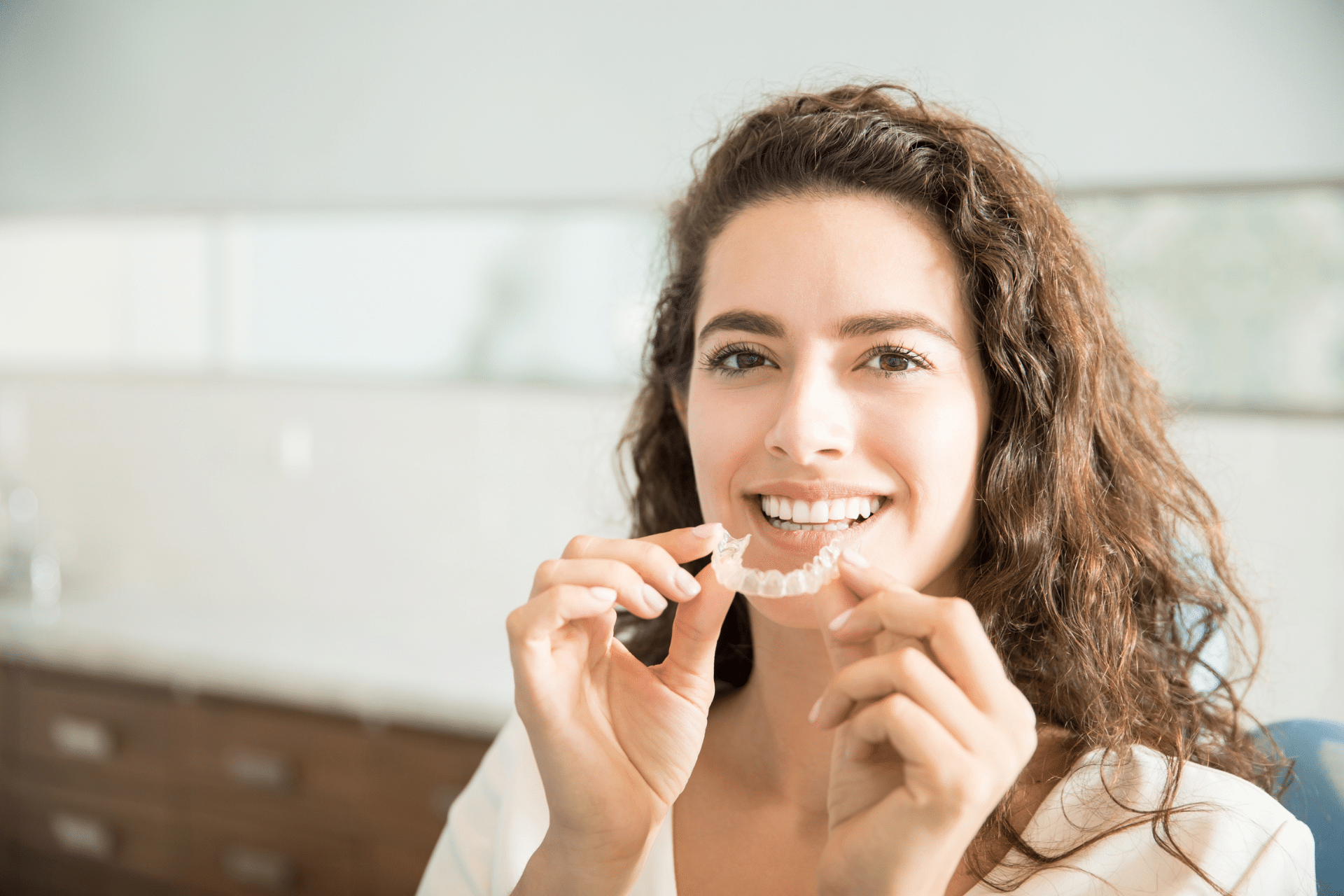 Patient holding clear aligners during an Invisalign consultation in Metuchen NJ
